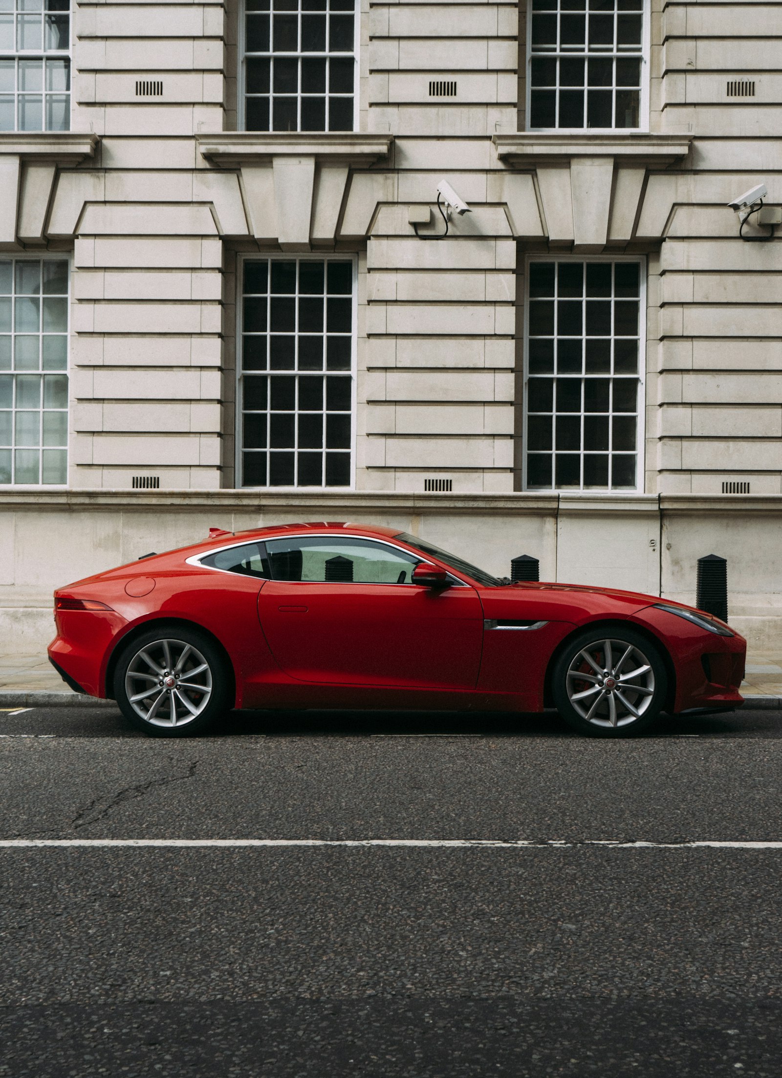 A red Jaguar coupé parked on a city street